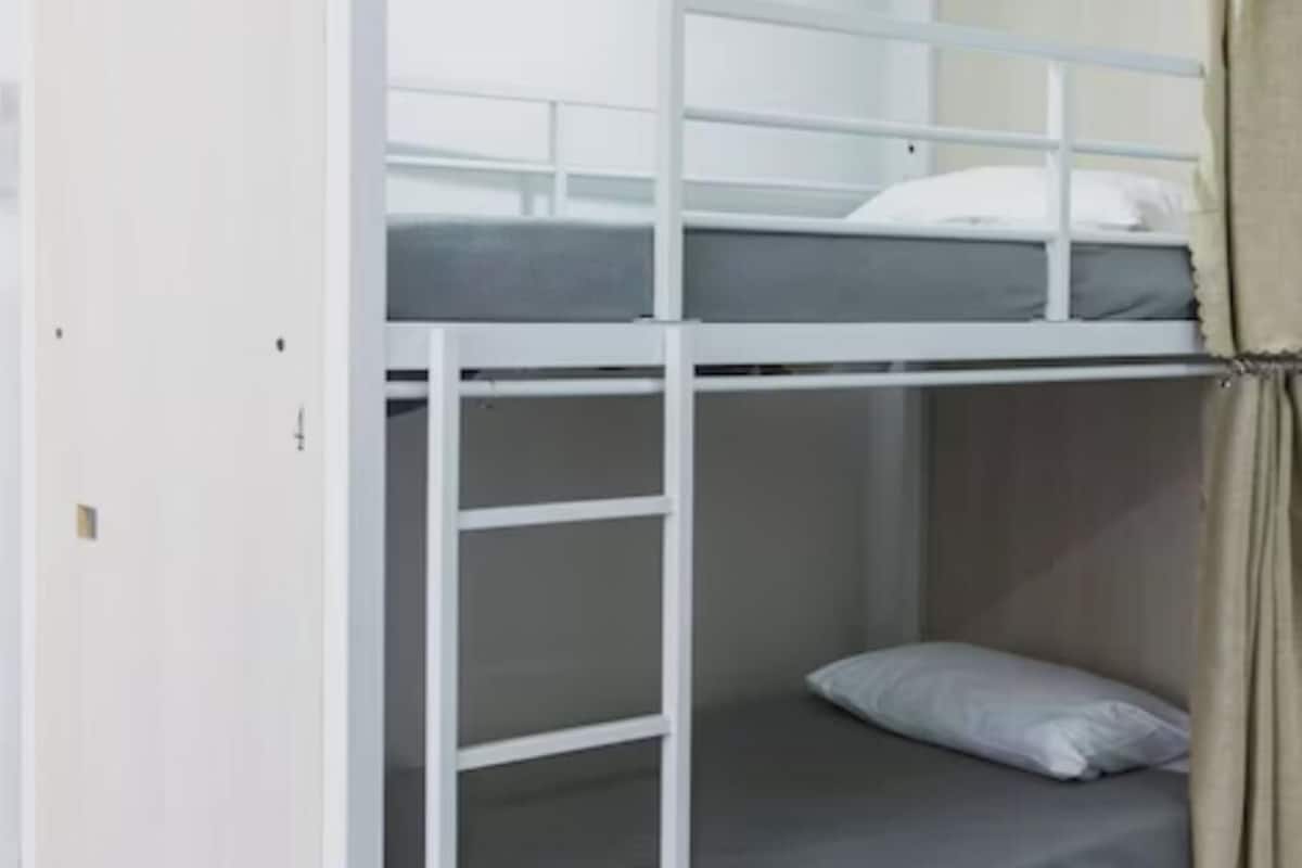 A bunk bed with a white frame and a grey mattress.