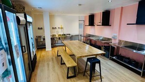 Una cocina moderna con una mesa de madera y bancos, un refrigerador y una estufa.