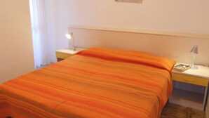 Una camera d'albergo con un letto, due comodini, una lampada da notte e un'opera d'arte a parete.