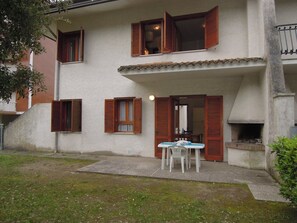 Un edificio a due piani con persiane in legno, un patio con tavolo e sedie e un camino.