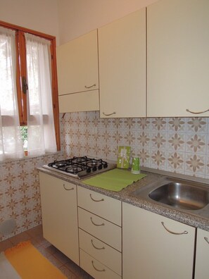 A kitchen with a gas stove, a sink, and cabinets. - Nice Flat for 6 Guests With Private Garden (San Michele al Tagliamento)