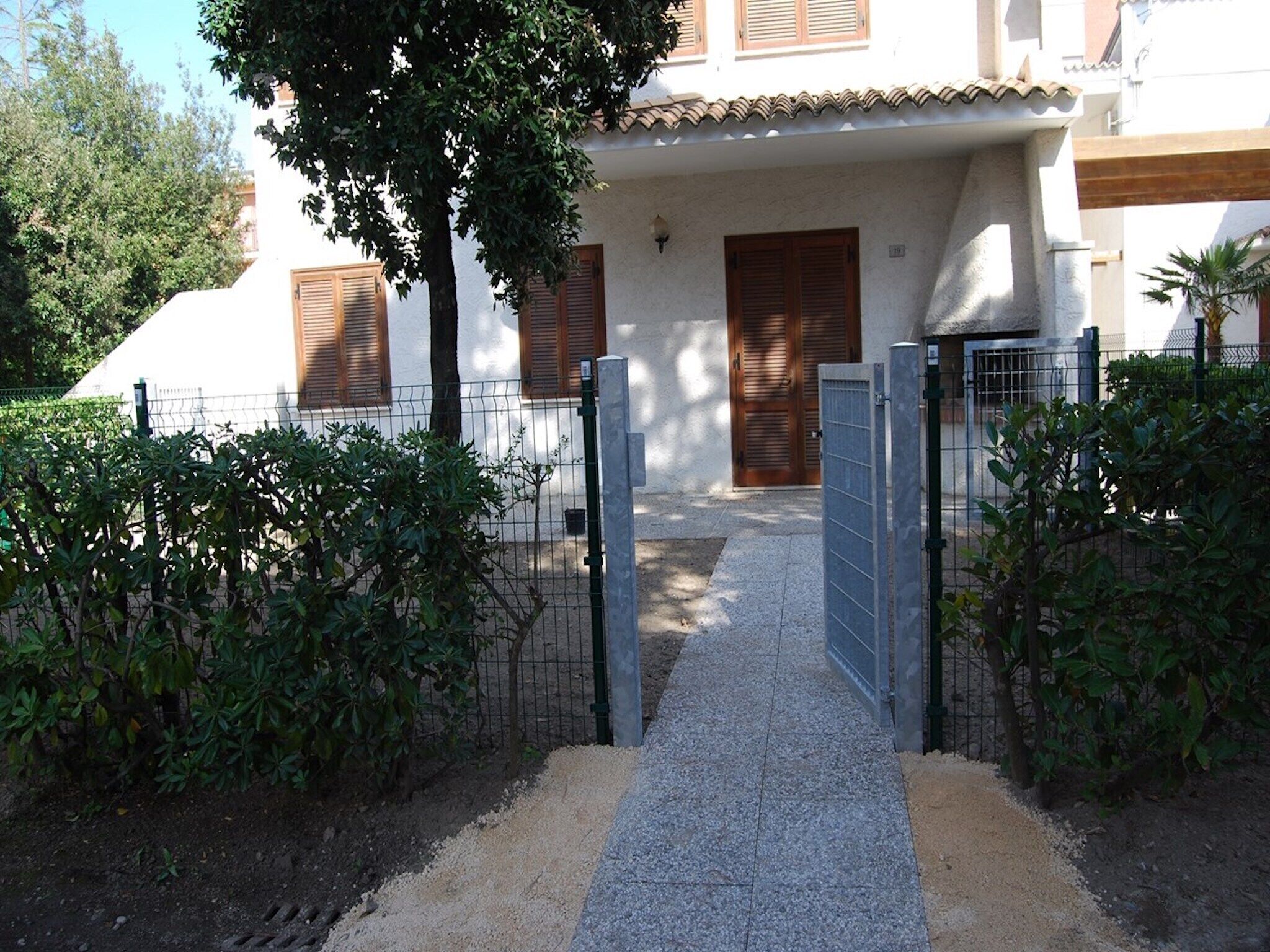 A gated entrance to a building with a tiled roof and wooden shutters.