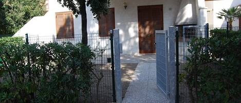 A gated entrance to a building with a tiled roof and wooden shutters.