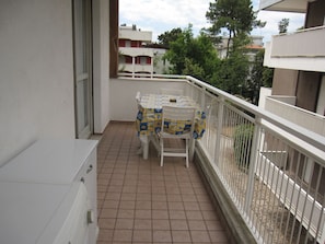 A balcony with a tiled floor, a table with a tablecloth, and a chair. - Modern Flat at Grado Pineda (Grado)
