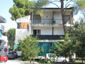 A multi-story residential building with balconies, parked cars, and trees. - Modern Flat at Grado Pineda (Grado)