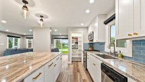 Une cuisine moderne avec des meubles blancs, un plan de travail en marbre et un lave-vaisselle.