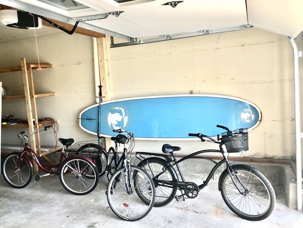 Eine Garage mit einem blauen Surfbrett an der Wand, zwei Fahrrädern und einer Holzleiter.