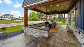 Une terrasse couverte avec des murs en pierre, une table à manger et des chaises.