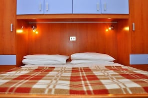 Ett hotellrum med en säng, en rutig filt, träpanel på väggarna och en ljusströmbrytare på väggen.