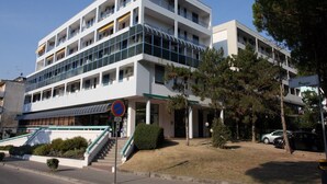 Un immeuble à plusieurs étages doté d’une architecture moderne, avec des balcons et une entrée abritée.