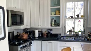 A modern kitchen with white cabinets, a stainless steel stove, a microwave, and a sink.