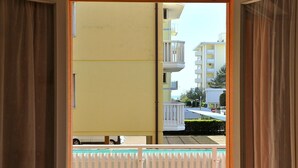 A view from a room with a sliding door to an outdoor balcony. The balcony has a white railing and a small pool. - Lovely Flat Just 150 m From the Beach (San Michele al Tagliamento)