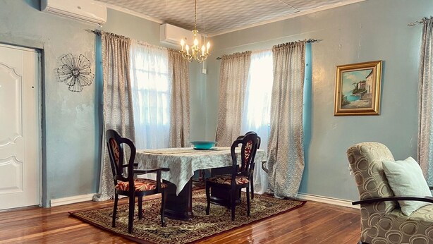 A dining room with a wooden floor, a table with chairs, and a chandelier. - Right between Guyana’s famous malls, family sized condo with safe neighborhood (Georgetown)
