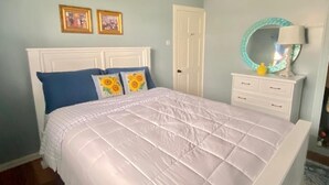A bedroom with a bed, a dresser, a mirror, and two framed pictures on the wall. - Right between Guyana’s famous malls, family sized condo with safe neighborhood (Georgetown)