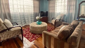 A living room with a sofa, armchairs, a TV, and a decorative vase. - Right between Guyana’s famous malls, family sized condo with safe neighborhood (Georgetown)