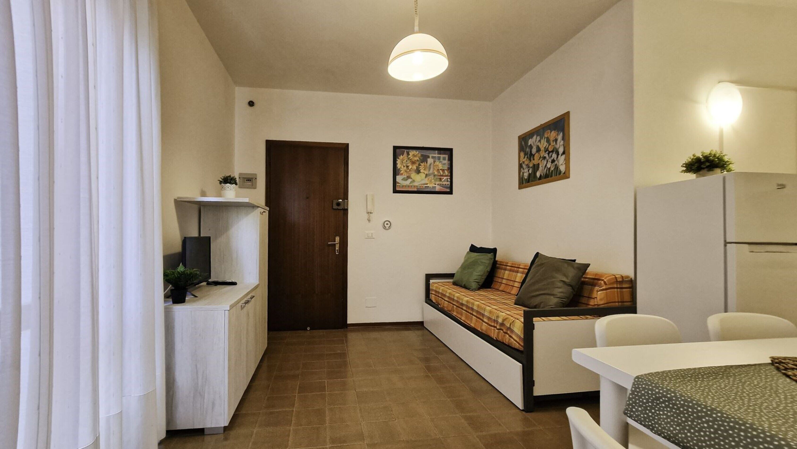 Un espacio habitable compacto con kitchenette, sofá, mesa de comedor y refrigerador.