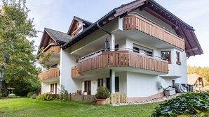 A multi-story residential building with balconies, a garden, and a satellite dish.