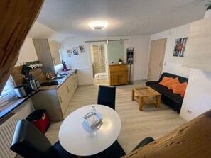 A compact living space with a kitchen, dining area, and a sofa.