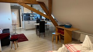 Ein kompakter Wohnraum mit Küchenzeile, Essbereich und einer Sitzecke mit rotem Teppich.