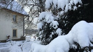 Ein Haus mit schneebedeckten Bäumen und einer sichtbaren Haustür.
