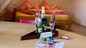 Ein Zimmer mit einem Bett, einem Tisch, einer Flasche, einem Glas und einer Karte.