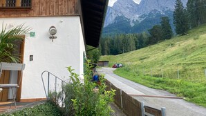 A wooden building with a white exterior, a visible staircase, and a view of a mountain range. - Apartment 'Kramernest' with Mountain View, Balcony and Wi-Fi (Grainau)