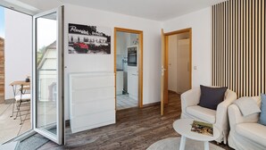 Un salon moderne avec un canapé, une table basse et une porte-fenêtre coulissante donnant sur un balcon.