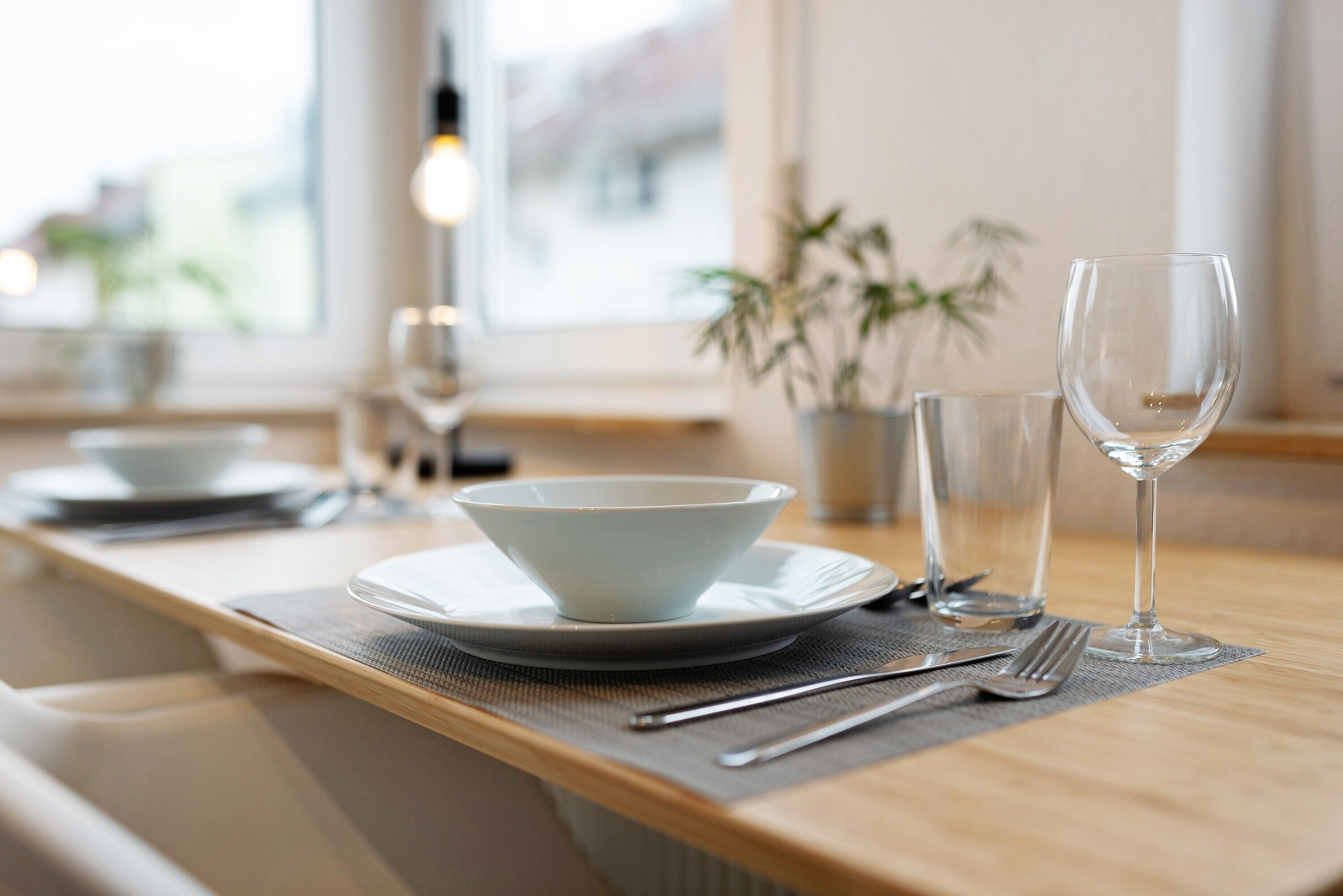 Une table à manger avec un saladier, un verre à vin et des couverts disposés sur un set de table.