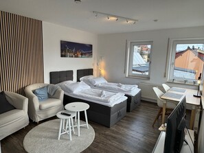 Una habitación de hotel moderna con una cama, dos sillas, una mesita y un televisor.