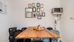 Un comedor con una mesa de madera, sillas, una bandeja con botellas y cuadros en la pared.