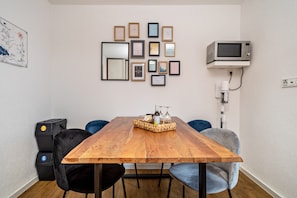 A dining area with a wooden table, chairs, a tray with bottles, and framed pictures on the wall.