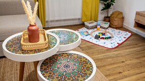 Una sala de estar con un sofá, una mesita con un jarrón decorativo, una bandeja estampada y un tapete de juego en el suelo.