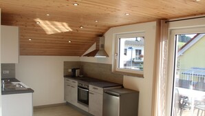 Een moderne keuken met houten plafond, ingebouwde apparatuur en een groot raam.