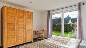Un dormitorio con cama, armario de madera, escritorio y silla.