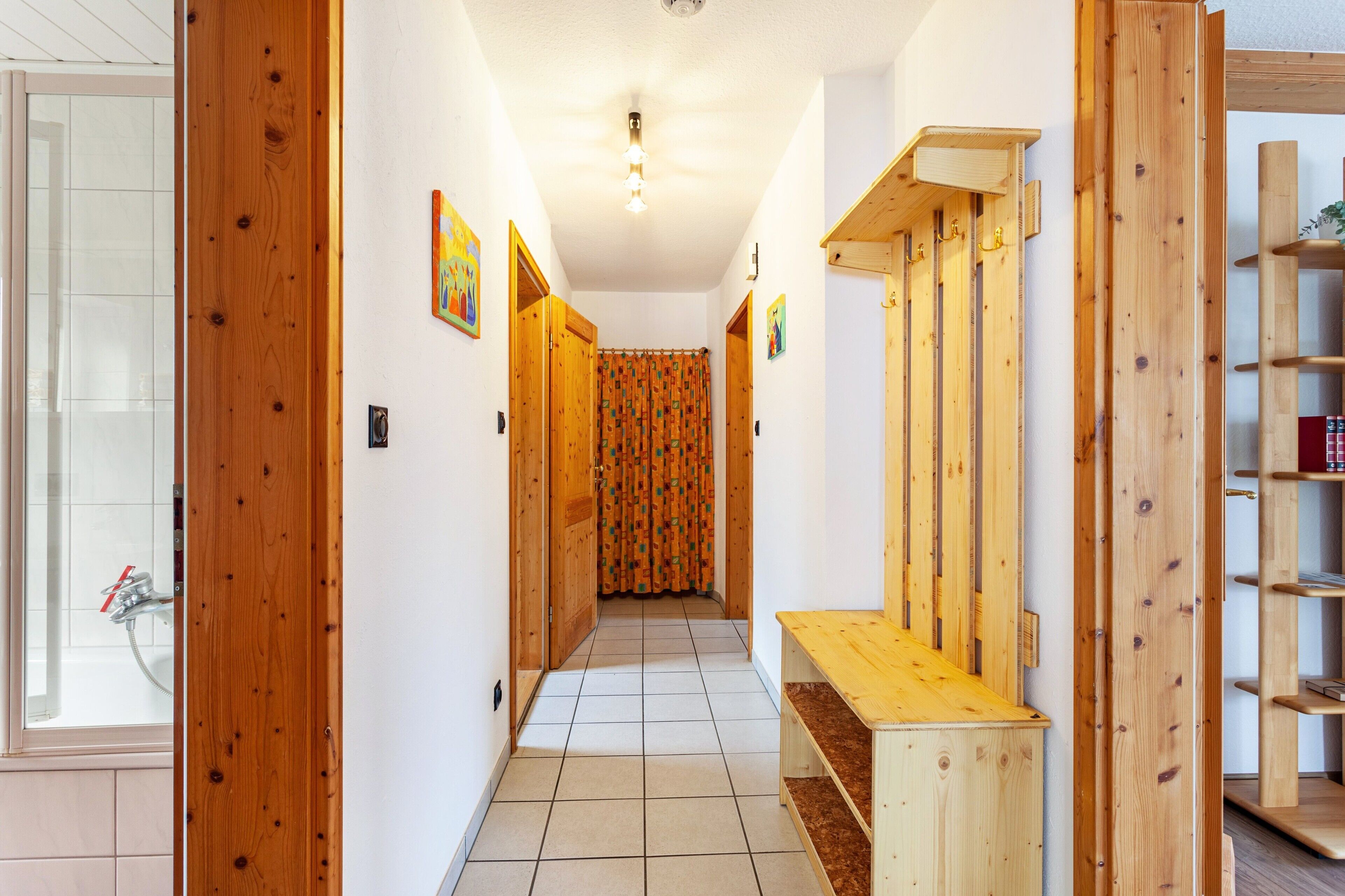 Un couloir avec des portes en bois, un banc et un espace douche.