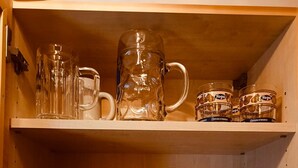 Un estante de madera con diferentes vasos, incluyendo un vaso grande, varias tazas y una tetera.