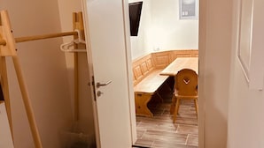 Una habitación con piso de madera, una puerta blanca, una silla de madera y una pequeña mesa.