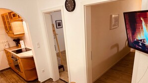 Una cocina con armarios de madera, estufa y comedor con mesa y silla.
