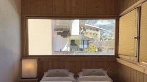 Ein Zimmer mit Holzwänden, einem Bett, einem Fenster und einer Lampe.