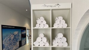 Ein Hotelkorridor mit einem an der Wand befestigten Poster einer Berglandschaft und einem weißen Regal mit ordentlich gerollten Handtüchern.