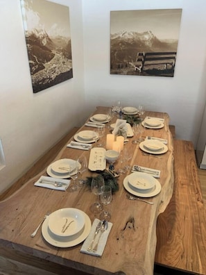 A dining table set with plates, cutlery, and glasses, surrounded by two framed photographs.