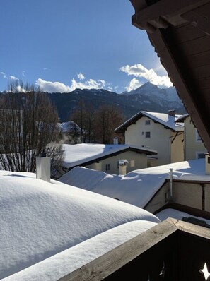 A residential area with snow-covered roofs, a mountain backdrop, and a clear sky.