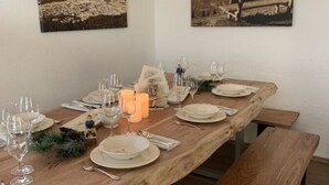 Ein Holztisch mit Tellern, Gläsern und Kerzen, an beiden Seiten begleitet von Bänken.