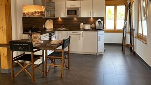 Eine moderne Küche mit weißen Schränken, einer Holzbalkendecke und einem Essbereich mit Tisch und Stühlen.