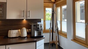 Eine Küche mit weißen Schränken, einer Kaffeemaschine und zwei Wasserkochern auf der Arbeitsfläche.
