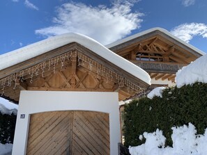 A wooden chalet with a snow-covered roof and a wooden door.
