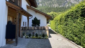Un refugio de montaña con fachada de piedra, vigas de madera y un patio empedrado.