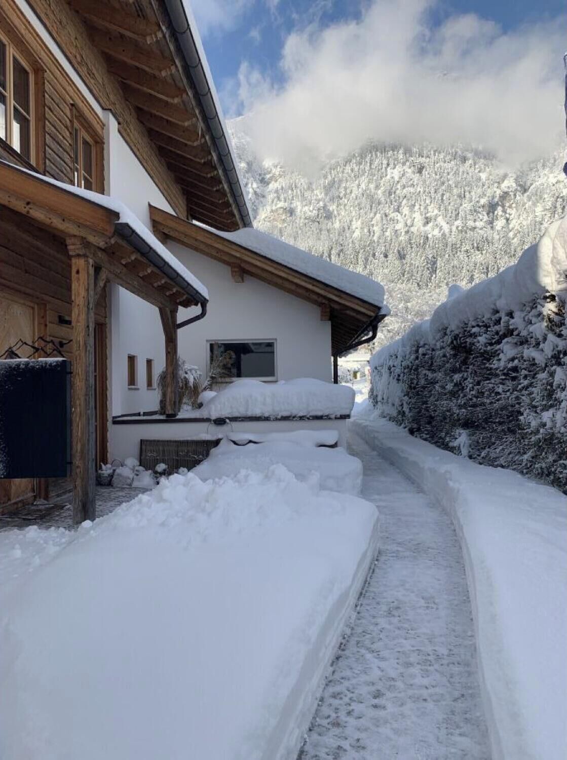Un edificio de madera cubierto de nieve, con cielo despejado y montañas al fondo.