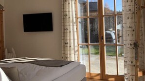 Un dormitorio con cama, televisor, puerta corrediza al exterior y una lámpara de techo.