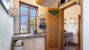Une cuisine avec une fenêtre, un évier, une cuisinière et une porte donnant sur une autre pièce.